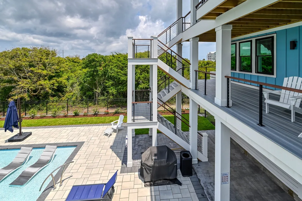 A lively exterior scene showing a spacious pool, comfortable outdoor seating, a staircase, and a grill area. The mood is vibrant and social, ideal for group barbecues, pool parties, and relaxing afternoons.
