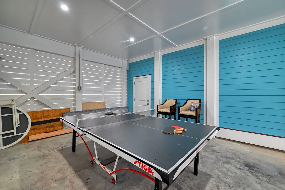 An energetic interior space featuring a ping pong table, blue accent wall, and a relaxed seating area. The atmosphere encourages group play, friendly competition, and memorable gatherings.