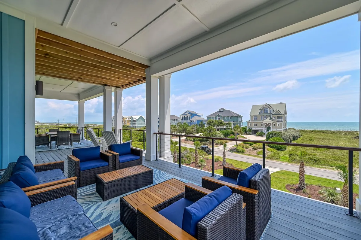 A comfortable exterior seating area overlooking the ocean, surrounded by lush greenery. The setting is perfect for relaxing with friends, reading, or soaking in a sunset. The clear ocean view and ample outdoor space evoke a tranquil, inviting mood.