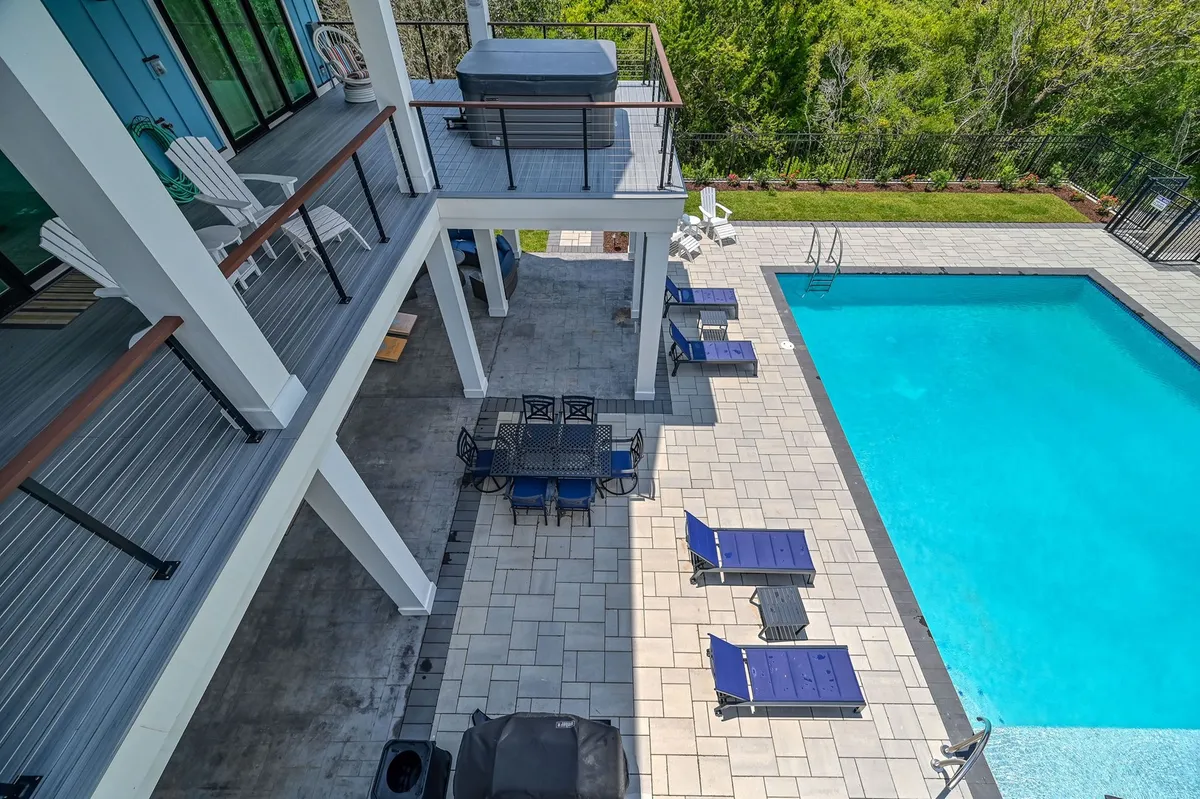An appealing outdoor area with a swimming pool, hot tub, lounge chairs, and an outdoor dining set, all set against a backdrop of open sky. The hot tub is a highlight, inviting guests to unwind, while lounge chairs and pool suggest spaces for both solo relaxation and group fun.