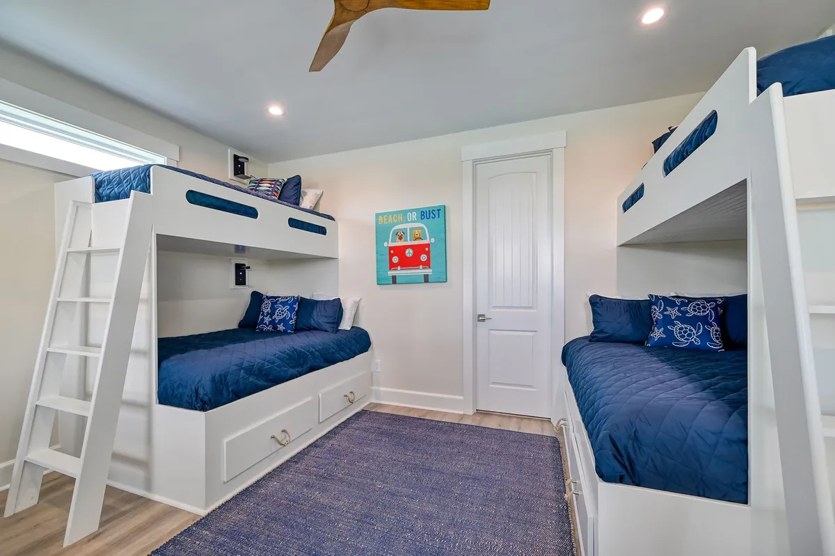 A cheerful kids' bunk suite with multiple bunk beds, vibrant wall art, a colorful rug, and plenty of space for play and rest. The setting feels whimsical and fun, tailored for young guests to enjoy.