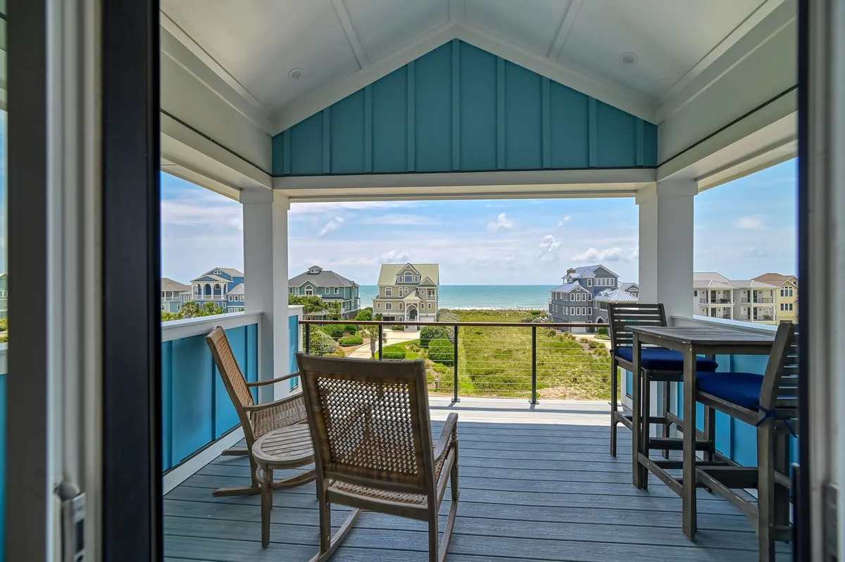 This image showcases balcony seating overlooking the ocean, with neighboring houses visible in the distance. The serene mood is enhanced by the tranquil ocean view and open skies, inviting guests to step outside, enjoy the fresh air, and contemplate the wider surroundings of Topsail Island.