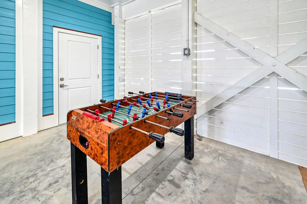 The image showcases an inviting foosball table against a blue accent wall, with a door leading to other spaces. The setup is ready for friendly matches and impromptu game nights, highlighting the property’s recreational amenities.