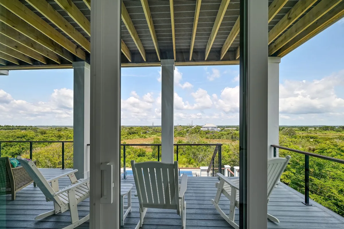 A tranquil exterior deck with comfortable deck chairs overlooking lush greenery and a vast open sky. The space is designed for relaxation, socializing, and taking in the surrounding natural beauty—ideal for watching sunrises or stargazing after a group meal.